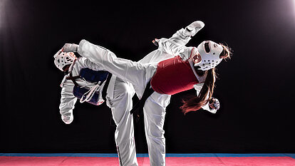 Junger Mann und Frau im Taekwondo-Kampf. Kampf zweier Schwarzgurte